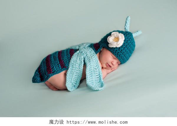 一个熟睡在2周龄新生女孩穿着一件绿松石蓝钩的蜻蜓服装的肖像